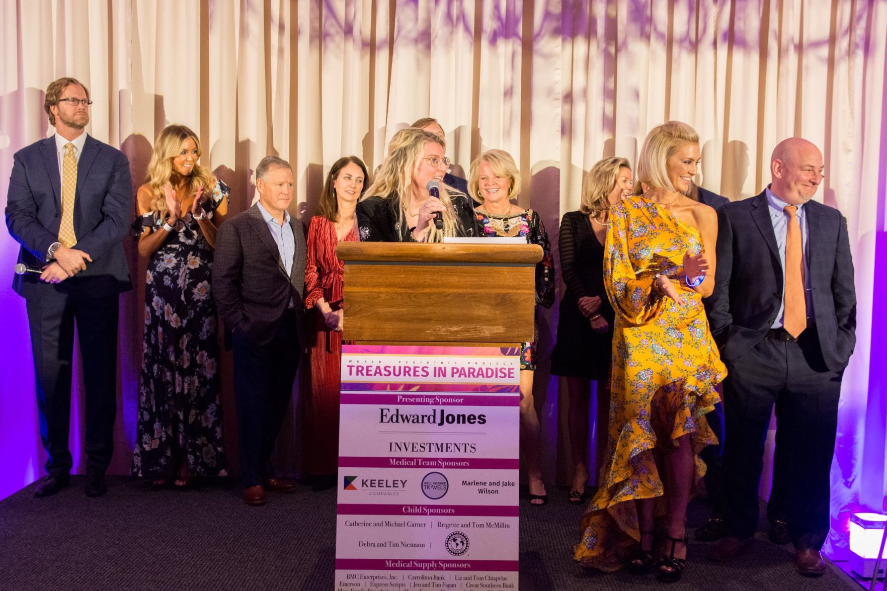 Kim Cella gives the introduction to the event among other speakers and co-chairs on stage at Treasures in Paradise